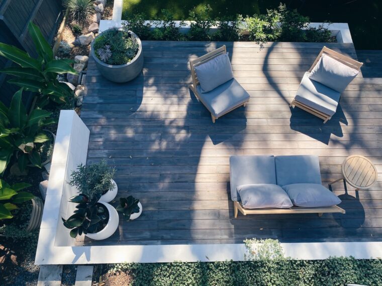 A bird's eye view of an outdoor deck with potted plants and gray furniture.